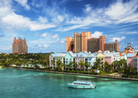 Beautiful scene of a boat, ocean, colorful houses and a hotel in Nassau, Bahamas on a summer sunny day